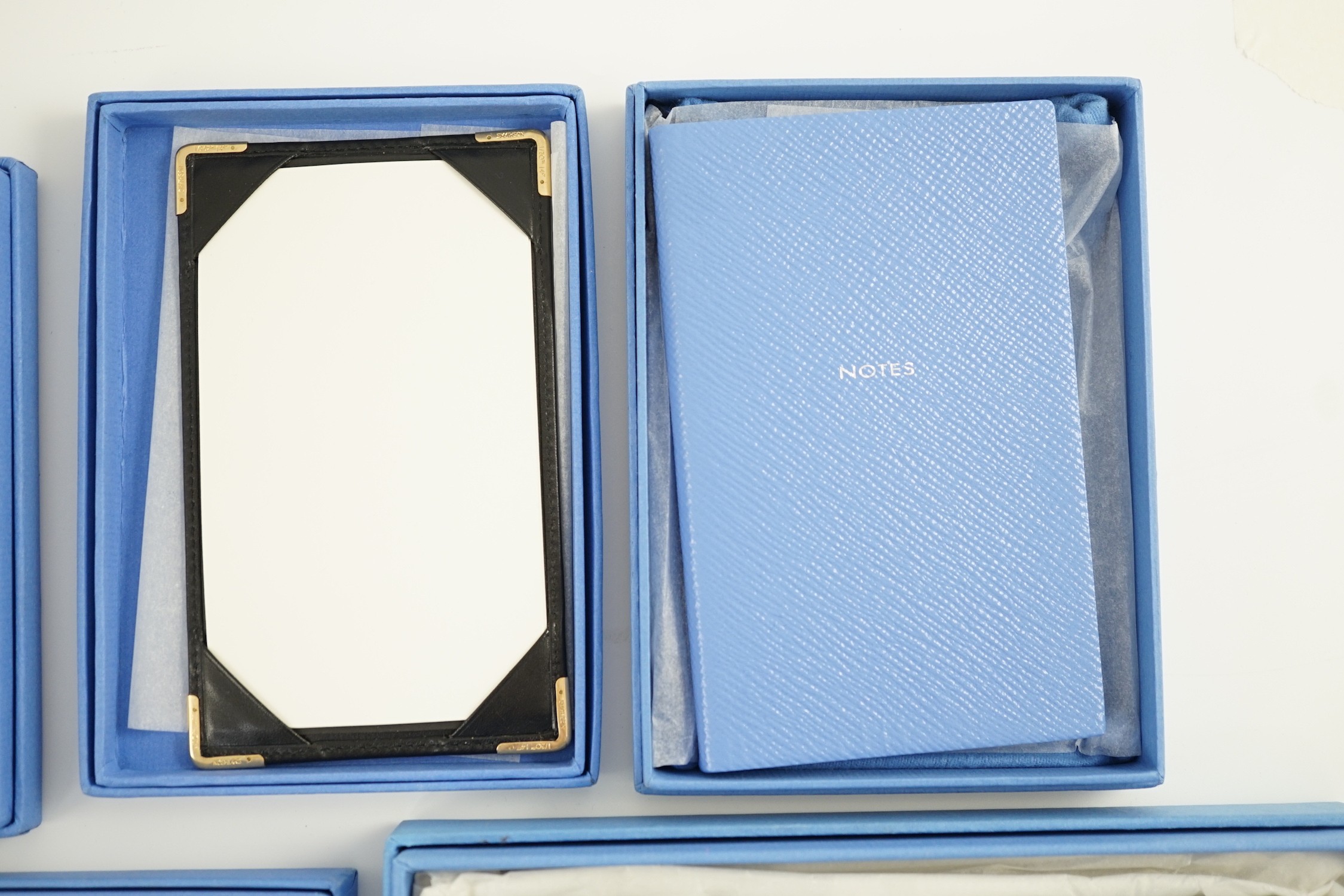 Smythson of London. A black leather notepad, 14cm, two moire silk address/telephone books, a pale grey leather purse,18cm, a Panama cornflower blue notebook, 14 cm and a duck egg blue purse, 20 cm. all boxed.